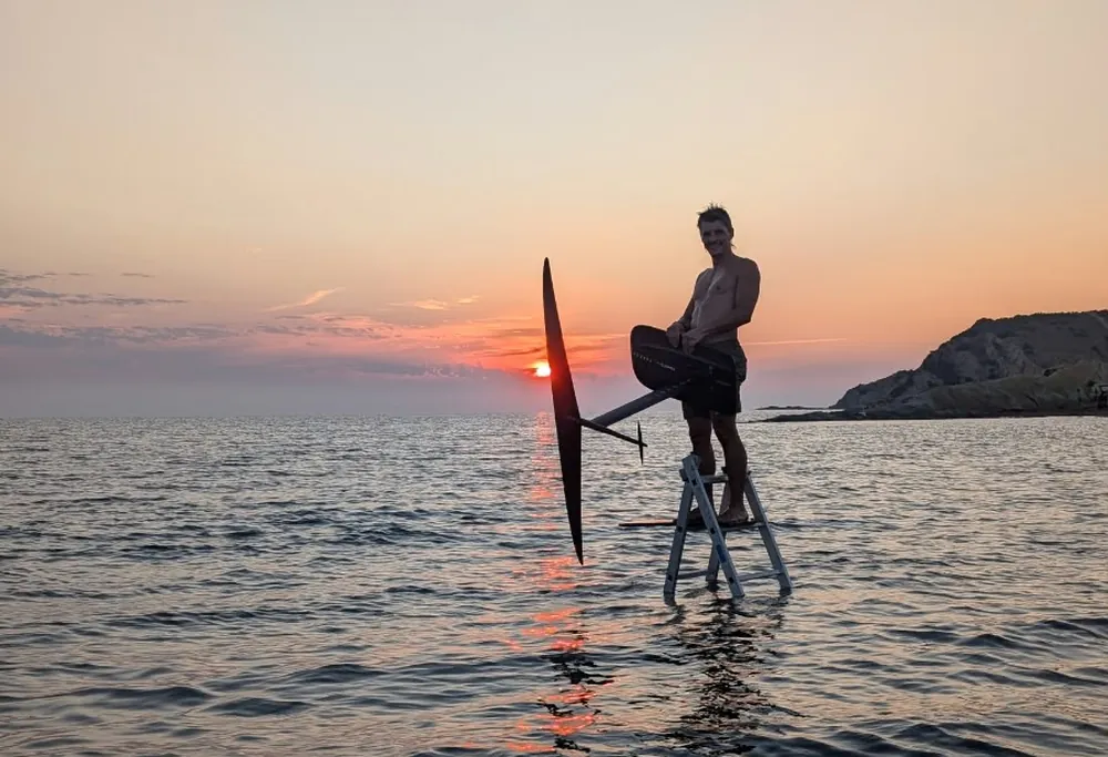 Rider en pump foil au coucher du soleil, soleil sur l’horizon